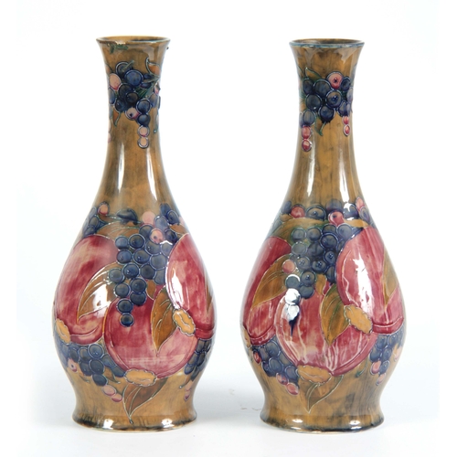 44 - A PAIR OF 20TH CENTURY MOORCROFT VASES decorated with pomegranates and grapes bearing green signatur... 