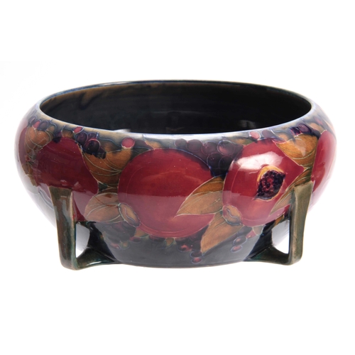 50 - AN EARLY 20TH CENTURY MOORCROFT BOWL DECORATED WITH POMEGRANATES having stylised feet - signed Willi... 