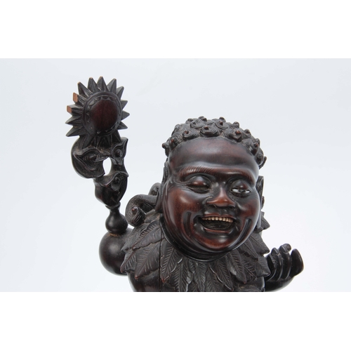 276 - A LATE 19th CENTURY CHINESE HARDWOOD FIGURE RIDING A FOO DOG with glass eyes and bone teeth standing... 