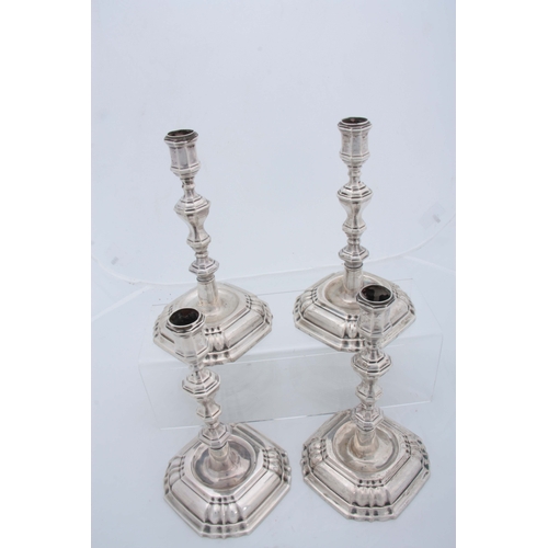 382 - A SET OF FOUR CONTINENTAL CAST SILVER CANDLE STICKS having moulded square bases, octagonal stems, ap... 