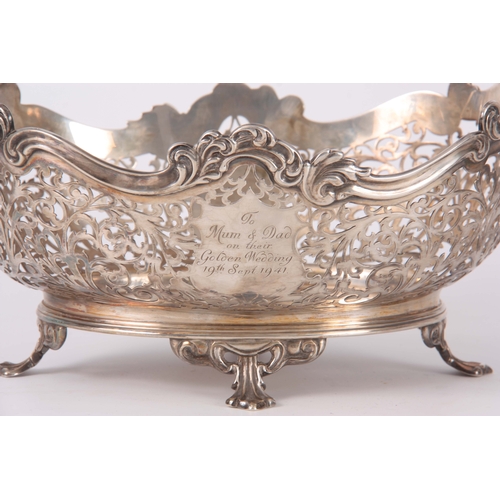 393 - A GEORGE V SILVER CENTER BASKET of pierced scrollwork design supported on four fluted feet 26.5cm wi... 