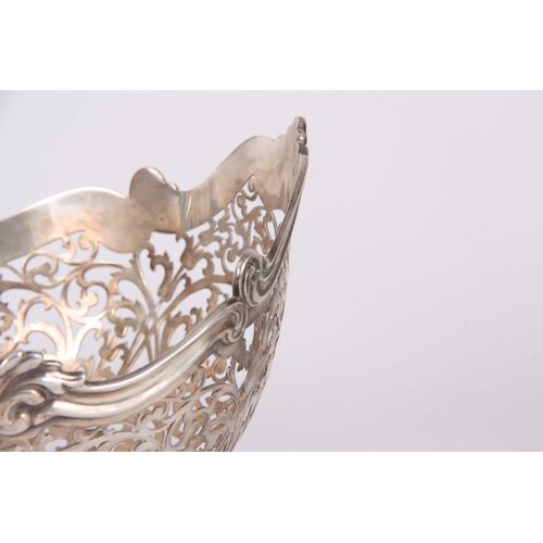 393 - A GEORGE V SILVER CENTER BASKET of pierced scrollwork design supported on four fluted feet 26.5cm wi... 