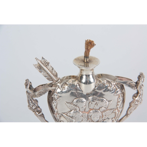 396 - A LATE 19th CENTURY SILVER HEART SHAPED OIL LAMP with relief winged cherub heads and fairy handles o... 