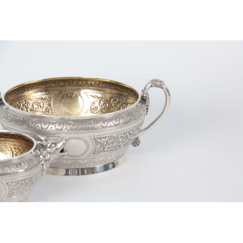 401 - A VICTORIAN SILVER AND GILT CREAM JUG AND SUGAR BOWL  having relief scroll-work panels and fine engr... 