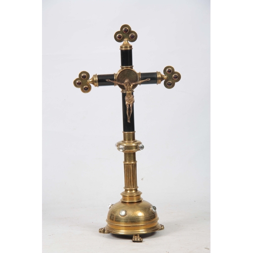 693 - A 19TH CENTURY BRASS AND EBONISED ALTER CRUCIFIX  having gilt bronze Christ, red clear glass cabersh... 