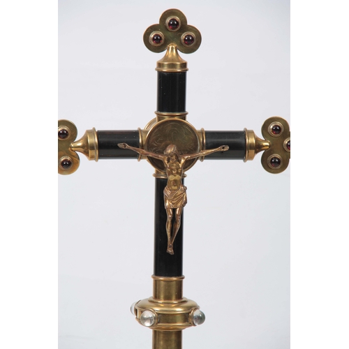 693 - A 19TH CENTURY BRASS AND EBONISED ALTER CRUCIFIX  having gilt bronze Christ, red clear glass cabersh... 