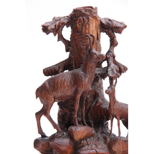 872 - A PAIR OF LATE 19TH CENTURY SWISS CARVED CANDLESTICKS with mountain goats beneath tree trunks on roc... 