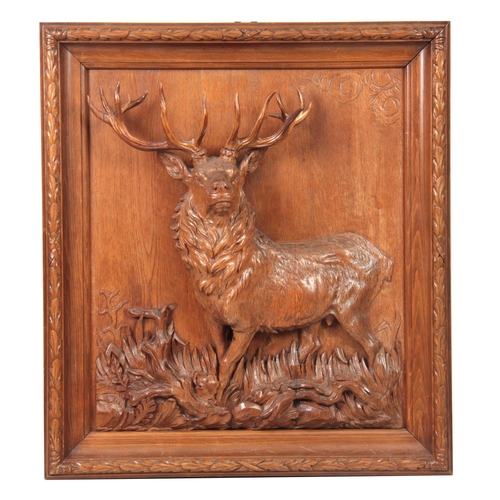 874 - A LATE 19TH CENTURY SWISS BLACK FOREST CARVED WALL PLAQUE depicting an imperial stag, surrounded by ... 