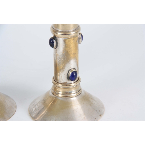 951 - A PAIR OF 20TH CENTURY ARTS AND CRAFTS SILVER PLATED CANDLESTICKS each mounted with 4 blue glass cab... 