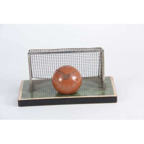 1099 - A VINTAGE NOVELTY DESK CLOCK MODELED AS A FOOTBALL with chrome goals and simulated grass plinth 22cm... 