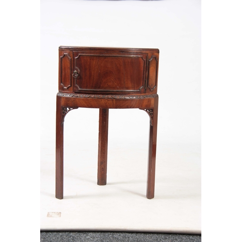 1141 - A GEORGE III MAHOGANY CORNER BEDSIDE TABLE with hinged door above a carved moulded edge, standing on... 