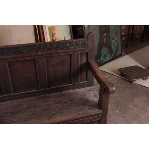 1159 - A RARE OVERSIZED 17TH CENTURY AND LATER JOINED OAK BOX SETTLE with an arcaded carved top rail, panel... 