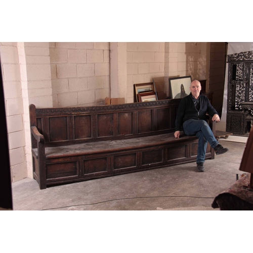 1159 - A RARE OVERSIZED 17TH CENTURY AND LATER JOINED OAK BOX SETTLE with an arcaded carved top rail, panel... 