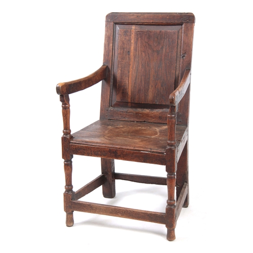 1180 - AN EARLY 18TH CENTURY OAK WAINSCOT CHAIR having fielded panel back with open arms and turned support... 