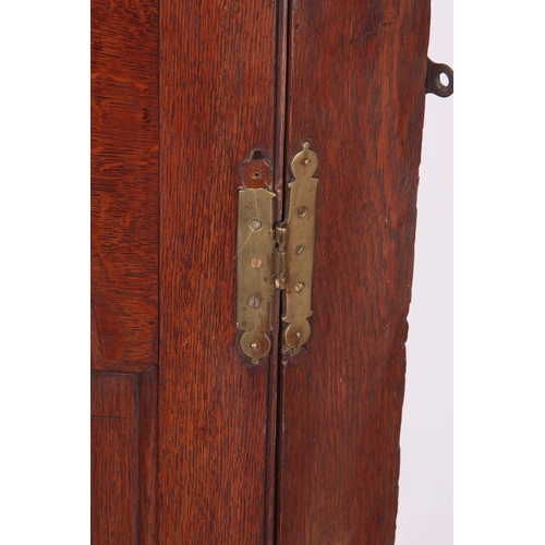 1193 - AN EARLY 18TH CENTURY OAK HANGING CORNER CUPBOARD with arched fielded panelled door, the interior ha... 