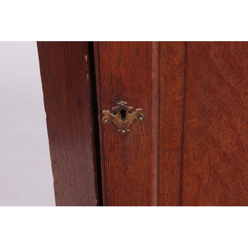 1193 - AN EARLY 18TH CENTURY OAK HANGING CORNER CUPBOARD with arched fielded panelled door, the interior ha... 