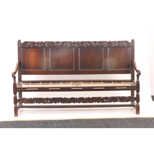 1221 - A CHARLES II JOINED OAK SETTLE with quadruple panelled back and bold leaf and shell carved top rail,... 