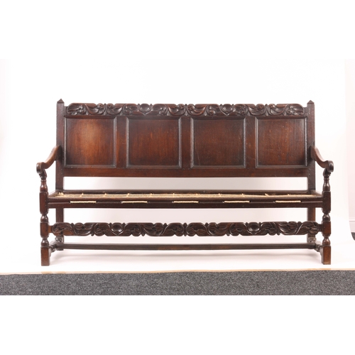 1221 - A CHARLES II JOINED OAK SETTLE with quadruple panelled back and bold leaf and shell carved top rail,... 