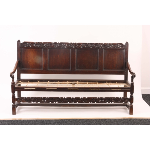 1221 - A CHARLES II JOINED OAK SETTLE with quadruple panelled back and bold leaf and shell carved top rail,... 