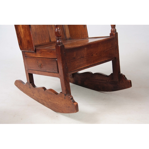 1236 - AN 18th CENTURY ELM LAMBING CHAIR with shaped back and headrest above open arms with panelled seat a... 