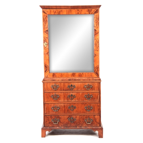 1285 - AN EARLY 18TH CENTURY FIGURED WALNUT MIRRORED CABINET ON CHEST with hinged door revealing a shelved ... 