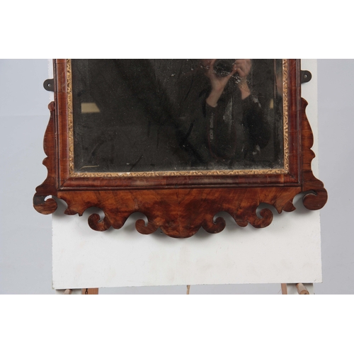 1293 - A LARGE GEORGE II WALNUT AND PARCEL GILT HANGING MIRROR with shaped fret cut frame and leaf carved m... 