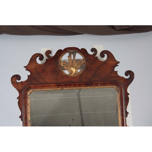 1293 - A LARGE GEORGE II WALNUT AND PARCEL GILT HANGING MIRROR with shaped fret cut frame and leaf carved m... 