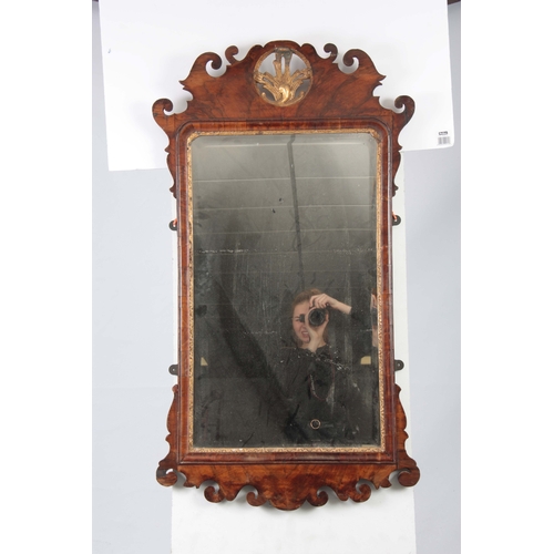 1293 - A LARGE GEORGE II WALNUT AND PARCEL GILT HANGING MIRROR with shaped fret cut frame and leaf carved m... 