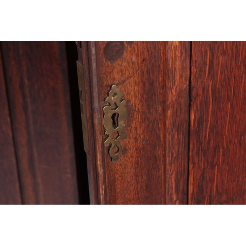 1308 - A MID 18TH CENTURY OAK HALL CUPBOARD with moulded cornice above a pair of arched fielded panel doors... 