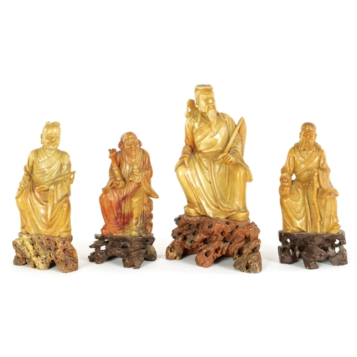 106 - A COLLECTION OF FOUR CHINESE SOAPSTONE CARVINGS modelled as seated immortals raised on pierced carve... 