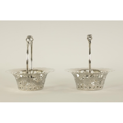 120 - A PAIR OF CHINESE SILVER SWEETMEAT BASKETS with double entwined loop handles on periced engraved bod... 