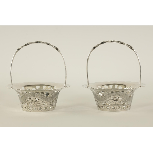 120 - A PAIR OF CHINESE SILVER SWEETMEAT BASKETS with double entwined loop handles on periced engraved bod... 