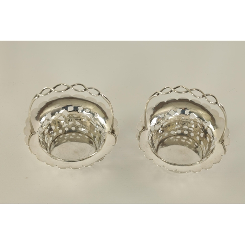 120 - A PAIR OF CHINESE SILVER SWEETMEAT BASKETS with double entwined loop handles on periced engraved bod... 