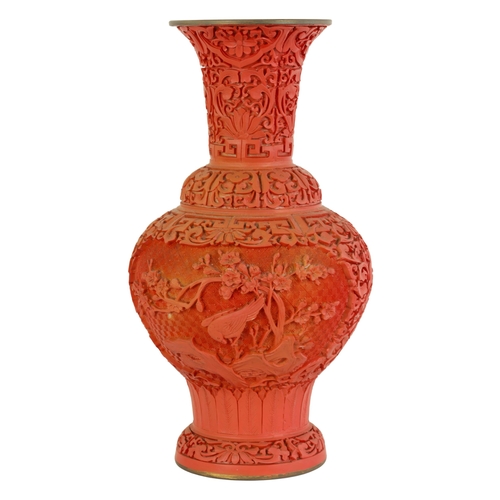 134 - AN EARLY 20TH CENTURY CHINESE CINNABAR VASE intricately carved with birds amongst blossoming branche... 