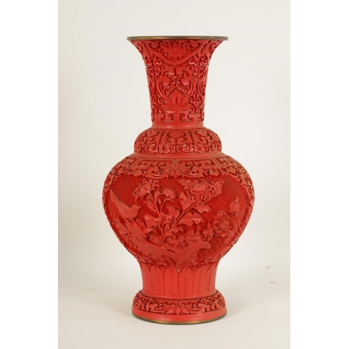 134 - AN EARLY 20TH CENTURY CHINESE CINNABAR VASE intricately carved with birds amongst blossoming branche... 