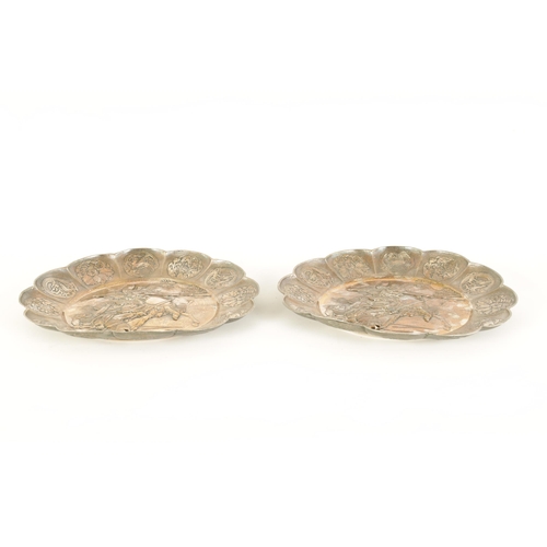 153 - A PAIR OF 19TH CENTURY SILVERED METAL CHINESE CIRCULAR HANGING PLAQUES the panelled petal-shaped bor... 