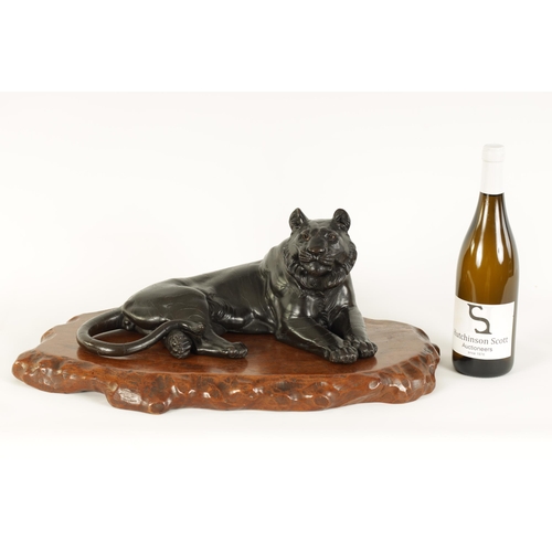 180 - A JAPANESE MEIJI PERIOD PATINATED BRONZE SCULPTURE modelled as a resting tiger on a shaped hardwood ... 