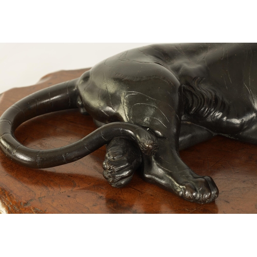 180 - A JAPANESE MEIJI PERIOD PATINATED BRONZE SCULPTURE modelled as a resting tiger on a shaped hardwood ... 