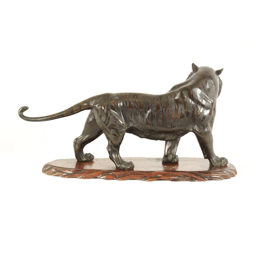 189 - A JAPANESE MEIJI PERIOD PATINATED BRONZE SCULPTURE modelled as a male tiger standing on a shaped har... 