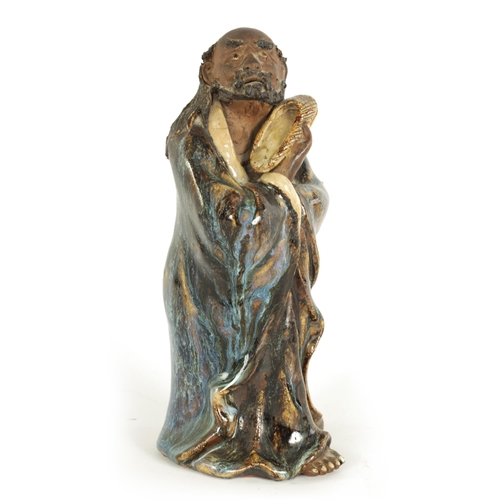 68 - A 19TH CENTURY CHINESE MAJOLICA SLIPWARE FIGURE depiciing an elder holding his slipper. (23cm high )