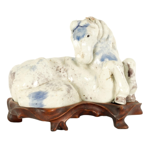 69 - A 19TH CENTURY CHINESE POTTERY WHITE AND BLUE SPASH GLAZED SCULPTURE OF A RECUMBENT HORSE mounted on... 