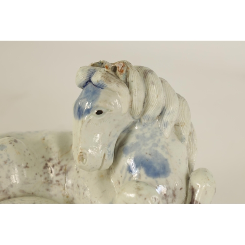 69 - A 19TH CENTURY CHINESE POTTERY WHITE AND BLUE SPASH GLAZED SCULPTURE OF A RECUMBENT HORSE mounted on... 