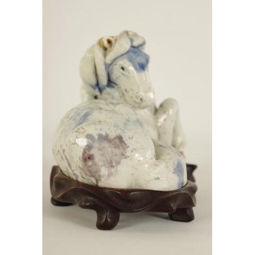 69 - A 19TH CENTURY CHINESE POTTERY WHITE AND BLUE SPASH GLAZED SCULPTURE OF A RECUMBENT HORSE mounted on... 