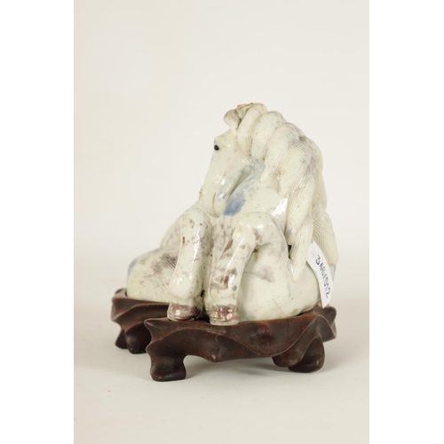 69 - A 19TH CENTURY CHINESE POTTERY WHITE AND BLUE SPASH GLAZED SCULPTURE OF A RECUMBENT HORSE mounted on... 