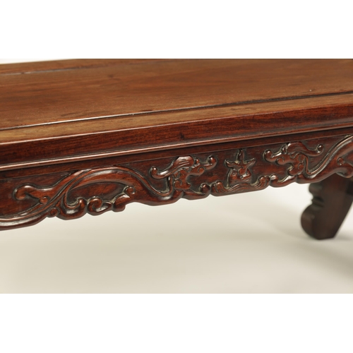 93 - A 19TH CENTURY CHINESE HARDWOOD ALTAR TABLE the panelled top with shaped sides and carved front depi... 