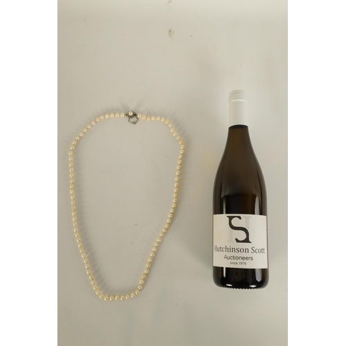 233 - A PEARL NECKLACE WITH 14CT WHITE GOLD CLASP fitted a safety catch and chain (81cm long)