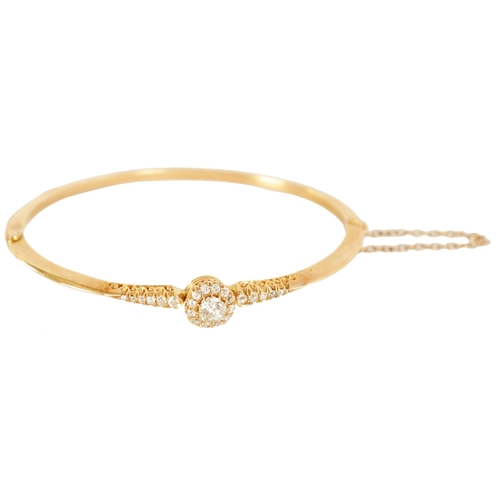 240 - AN 18CT GOLD AND DIAMOND SET LADIES BANGLE with raised centre flower head setting and tapered set sh... 