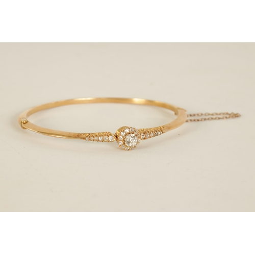 240 - AN 18CT GOLD AND DIAMOND SET LADIES BANGLE with raised centre flower head setting and tapered set sh... 