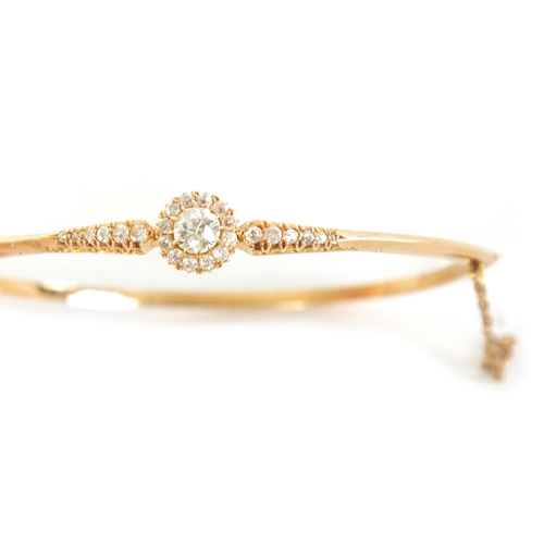 240 - AN 18CT GOLD AND DIAMOND SET LADIES BANGLE with raised centre flower head setting and tapered set sh... 