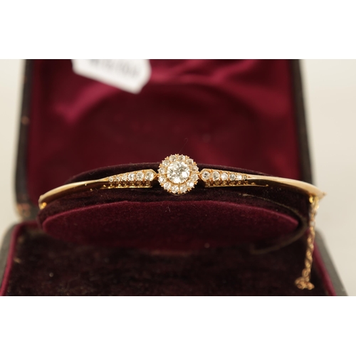 240 - AN 18CT GOLD AND DIAMOND SET LADIES BANGLE with raised centre flower head setting and tapered set sh... 